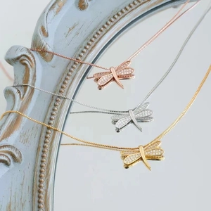 Dettaglio dei ciondoli a libellula in oro, argento e oro rosa con pietre di zircone