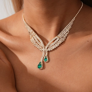 Detail of necklace featuring pear-shaped emerald green stones and diamond accents