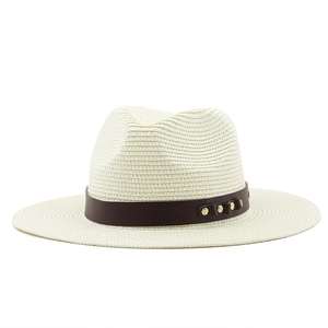 Détail d'un chapeau de paille ivoire avec bande en cuir marron et trois clous dorés