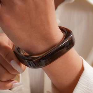 Close-up shot of a square tortoiseshell resin bangle bracelet on a female wrist.