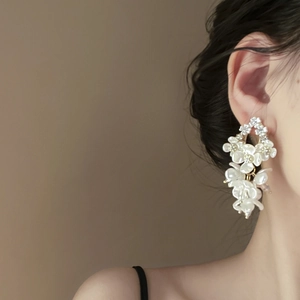Macro detail of long shell flower tassel earrings with zircons on model's side profile