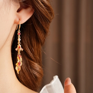 Close-up of vintage koi fish earrings with enamel finish and tassels on a model