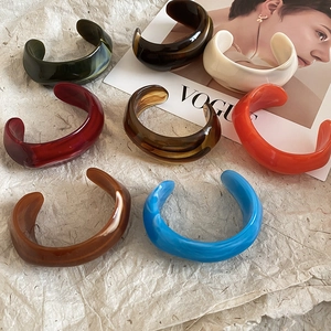 Detailed top view of assorted colorful acrylic resin bangles on a stylish VOGUE magazine backdrop