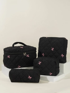 4-piece set of black quilted makeup bags with pink bow embroidery on a display stand