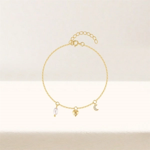 Macro shot of gold S925 silver bracelet featuring heart, moon, and pearl charms