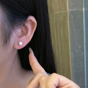 Detail view of a 925 sterling silver stud earring with oval-cut cubic zirconia on a model