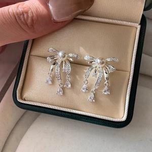 Silver bow tassel earrings with white pearls and drop zircons in a jewelry box