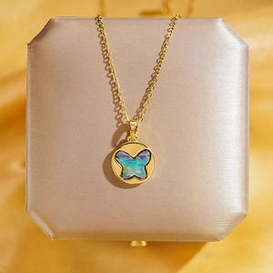 Collier papillon doré avec pendentif en nacre irisée sur un coffret à bijoux chic