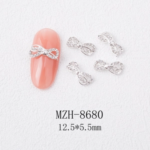 Macro detail of 12.5x5.5mm alloy bowknot nail charms with crystals on pink nails
