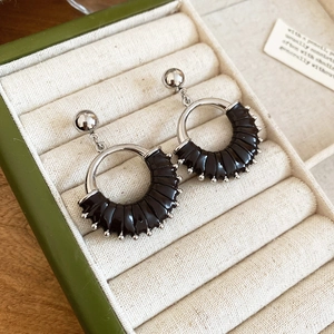 Close-up of retro black leather hoop earrings with silver beaded trim and stud details