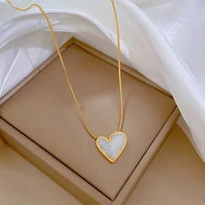Macro detail of gold-plated titanium steel necklace with white mother-of-pearl heart pendant