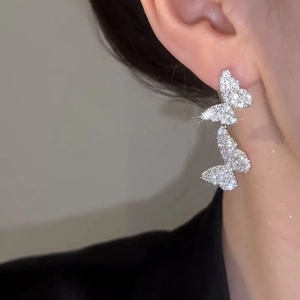 Elegant silver-colored butterfly earrings with sparkling crystals shown on a model