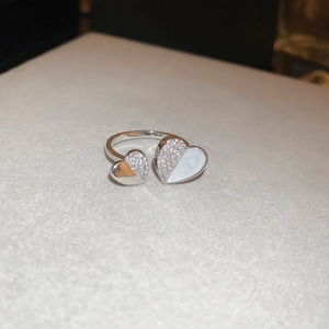 Macro detail of silver adjustable ring featuring zircon and white shell heart charms