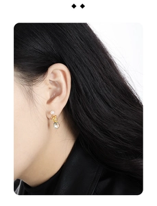 Close-up of elegant gold earring with white pearl and teardrop zircon on female model