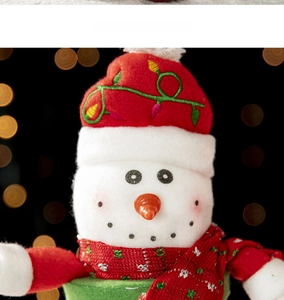 Close-up of plush snowman Christmas decoration with red knitted hat and warm bokeh lights