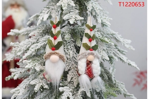 Close-up of plush Christmas gnome ornaments hanging on a snowy holiday tree branch