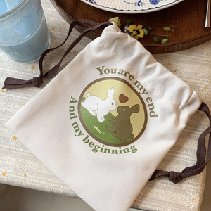Close-up of rabbit illustration canvas drawstring bag on lace tablecloth