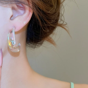 Close-up of model wearing transparent iridescent acrylic C-shape hoop earrings
