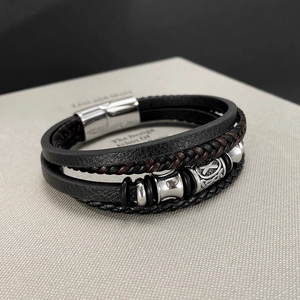 Detail of multi-layer black and brown leather bracelet with silver celtic knot metal bead