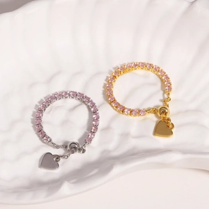 Detail of adjustable rings with pink zircon stones and heart pendants in gold and silver