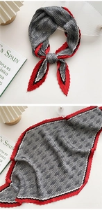 Detailed view of houndstooth pleated scarf with red edges in a lifestyle setting