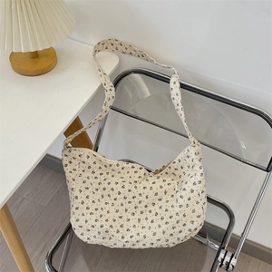 Floral canvas hobo bag with blue flower pattern draped over a clear acrylic chair