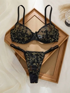 Détail d'un ensemble soutien-gorge en dentelle noire avec broderie florale dorée de luxe