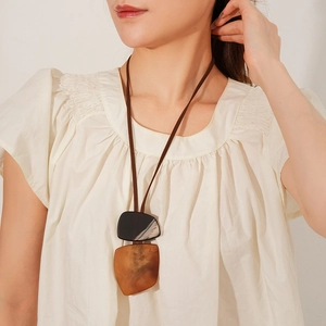 Detail of a vintage long necklace with amber marble resin pendants and a brown leather cord