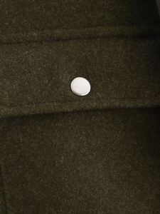 Vue détaillée macro du tissu en tweed vert foncé avec un bouton-pression en métal argenté