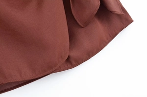 Detail van de zoomstiksels en textuur van de roestbruine halterjurk voor dames