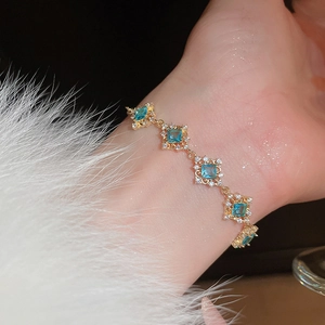 Close-up of golden bracelet with square blue zircon stones and white fur cuff details