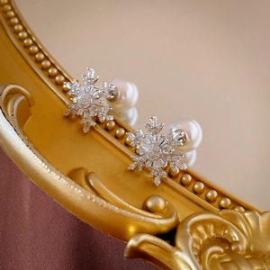 Detailed macro view of snowflake earrings with zircon stones and elegant artificial pearls