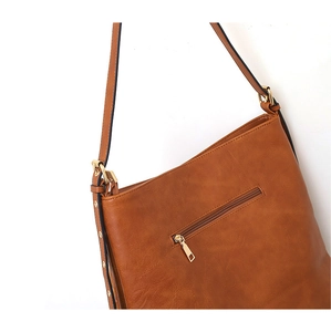 Détail d'un sac à bandoulière marron en similicuir avec clous dorés et fermeture éclair