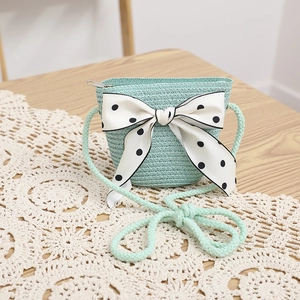 Detail of mint green woven straw bag featuring a large polka dot silk bow decoration