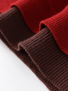 Détail de maille côtelée rouge et marron montrant la texture douce et les coutures