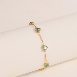 Dettaglio di un bracciale a catena dorata con vari zirconi blu a forma di cuore