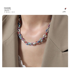 Close-up of a colorful link necklace worn by a model in a beige blazer for a trendy look
