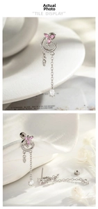 Detail of silver asymmetric tassel earrings featuring moon and pink flower motifs