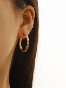 Macro shot of 18k gold plated hoop earrings showing refined diamond pattern texture