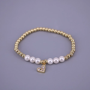 Detail of beaded bracelet featuring gold round beads, white pearls and a paved heart charm