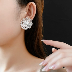 Detailed view of silver flower earrings with center pearl on a model's ear