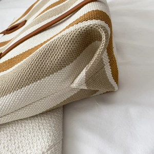 Large striped canvas tote bag with brown leather trim and high-density fabric details