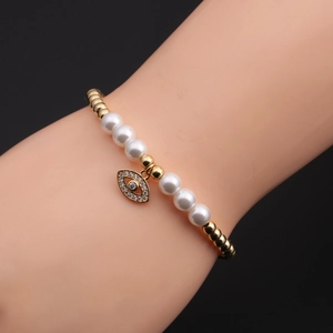 Close-up of a beaded pearl bracelet with evil eye pendant on a woman's wrist