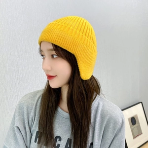 Side view of a vibrant yellow knitted winter hat with ear flaps for cold protection