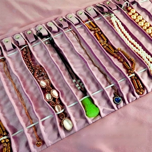 Close-up of pink velvet jewelry roll with snap hooks for organized necklace storage