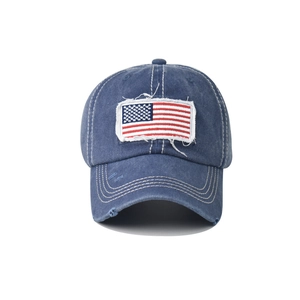 Close-up of vintage washed blue cotton baseball cap with American flag embroidery and distressed holes