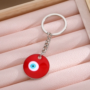 Red enamel Turkish evil eye keychain with silver metal ring on pink velvet background