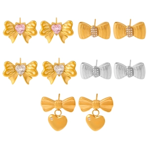 Gold and silver bow earrings set with pink heart zircons and rhinestones on white base