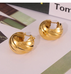 Macro detail of French retro gold-plated twisted hoop earrings with polished metal texture