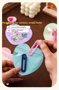 Detail showing the process of placing a purple hair clip into a cyan heart shaped resealable bag